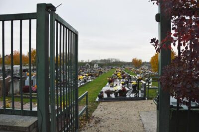 Entrée du cimetière, allées gazonnées, nombreuses potées et godets fleurs